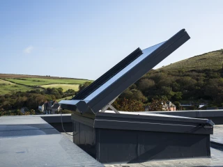 open rooflight installed on a rooftop, green hills and scenery seen in the background