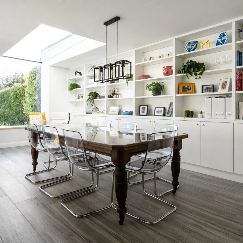 table in middle of room with book case behind next to an eaves skylight