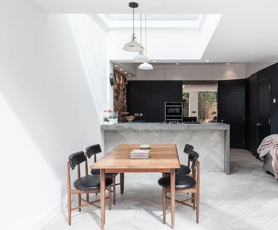 flat skylight over wooden dining table in modern white kitchen diner with black cupboards