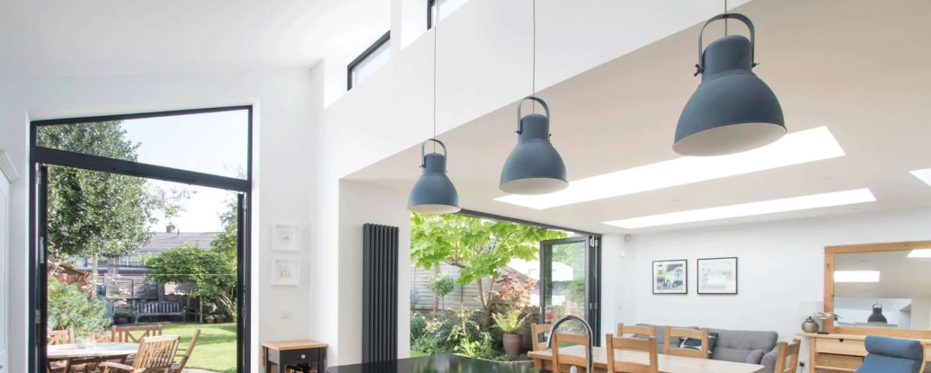 Shows a kitchen with hanging lights and lots of natural daylight shining through