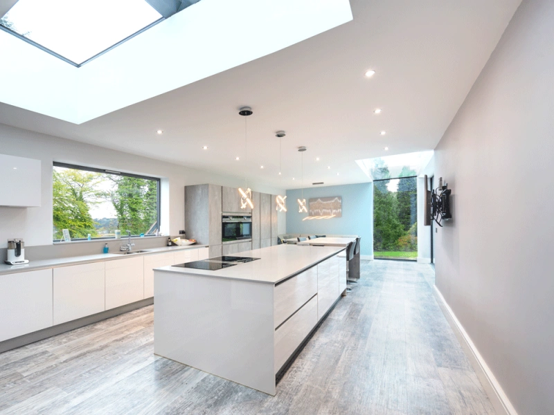 kitchen with white and marble cabinets. Above the kitchen island is a large skylight which is letting lots of natural daylight in
