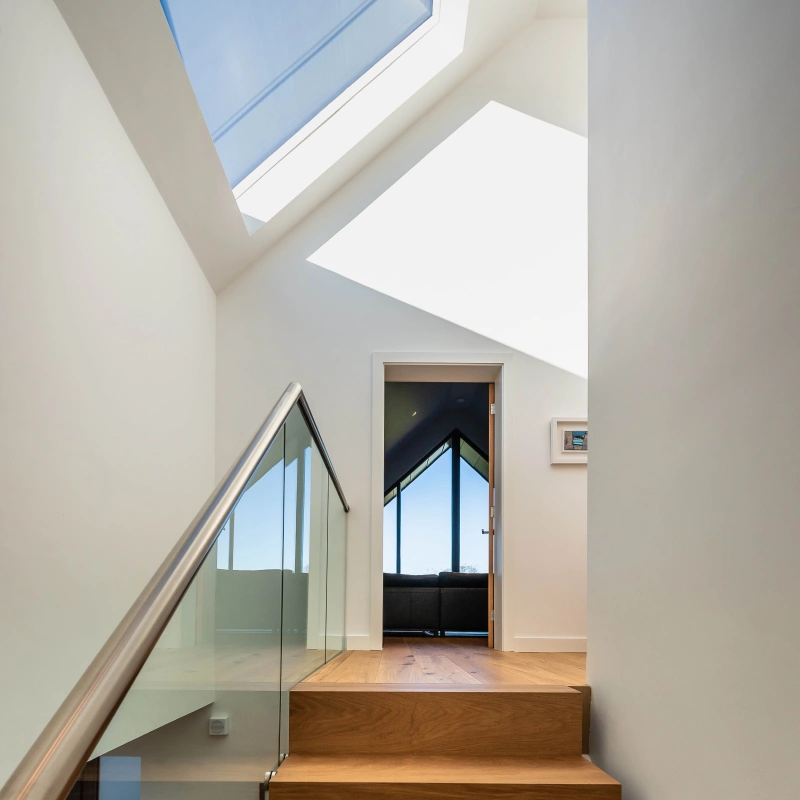 A staircase leading to top of staircase where there is a angled roof window