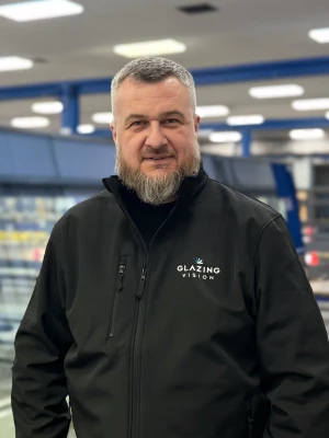 A man with grey hair and beard smiling at the camara.