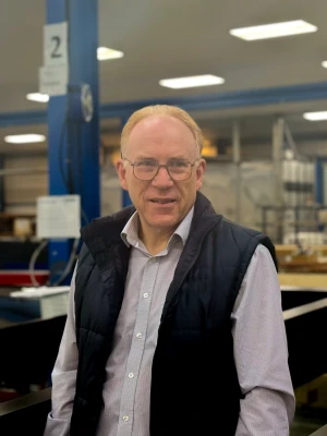 A older man with ginger and grey hair with glasses smiling at the camara