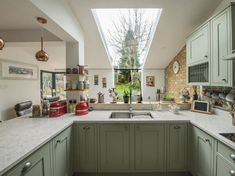 Skylight in kitchen over looking the sink and green cabinets