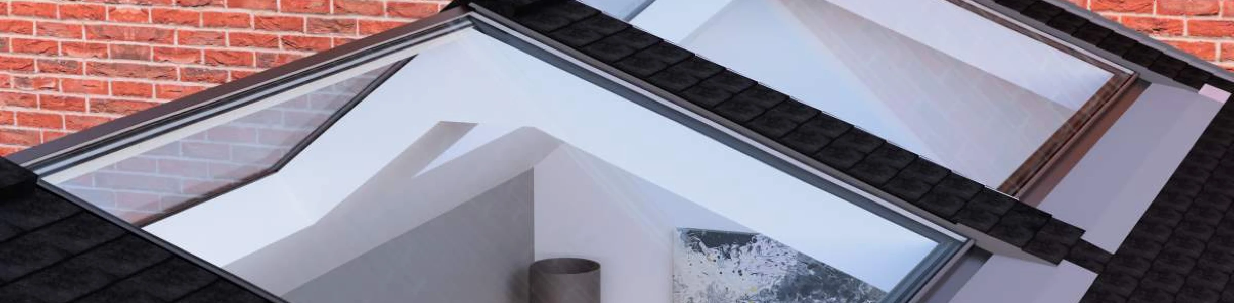 Two skylights on a sloped roof provide a view into a brightly lit interior space featuring a gray lamp and a piece of art on the wall. The roof is covered in dark shingles, and a brick wall is visible in the background.