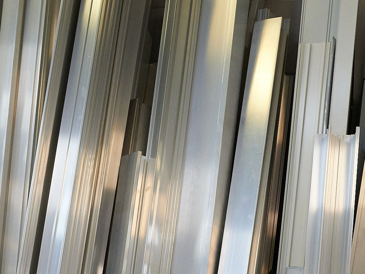 Metal strips of various lengths and widths are stacked together, reflecting light and creating a shiny, textured surface.